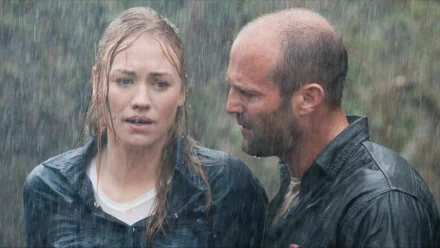 HD desktop wallpaper from the movie Killer Elite, depicting two characters in a rain-soaked, intense moment.