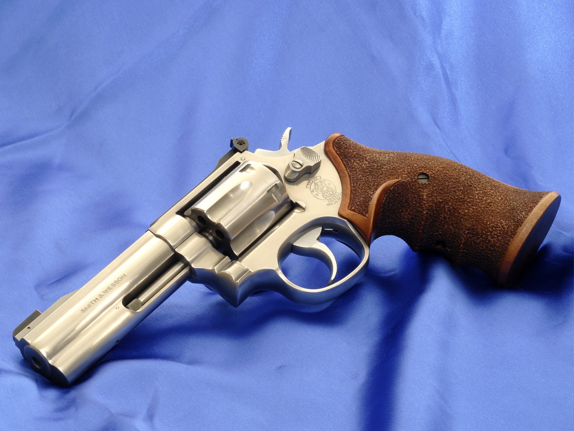 Man-made Smith & Wesson revolver with wooden grip resting on blue cloth — HD PC desktop wallpaper/background.