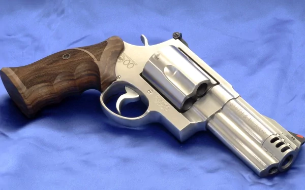 Close-up of a man-made Smith & Wesson stainless steel revolver with wood grip resting on blue fabric, HD PC desktop wallpaper and background.