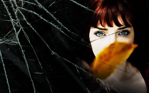 HD PC desktop wallpaper: close-up of a red‑haired model/celebrity with striking blue eyes, an orange leaf partially covering her face set against a cracked‑glass texture.