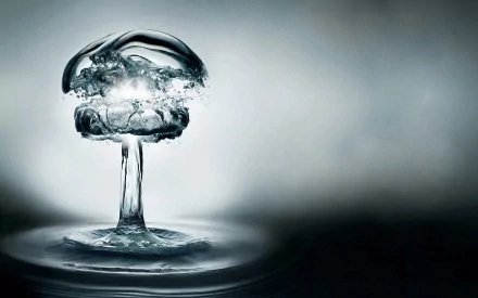 Abstract HD desktop wallpaper showing an artistic water formation resembling an atomic bomb explosion against a smooth gray background.