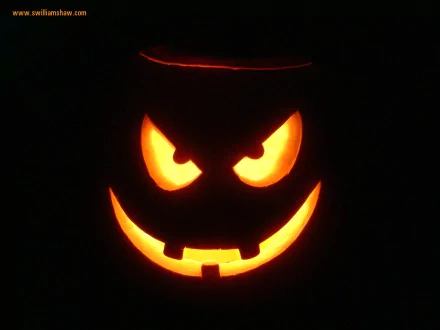 A glowing carved pumpkin with a menacing face illuminates the darkness, capturing the spooky essence of Halloween in this HD desktop wallpaper and background.