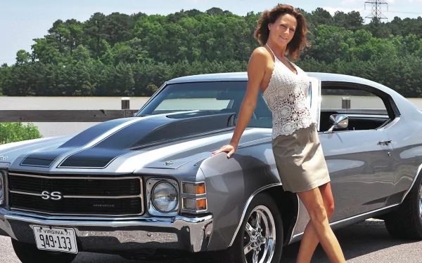 HD PC desktop wallpaper featuring a woman posing confidently beside a classic SS muscle car with lush greenery in the background, blending girls and cars themes.