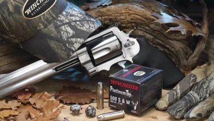 Man-made HD PC desktop wallpaper showing a Smith & Wesson Model 500 revolver, Winchester .500 S&W ammo box, spent rounds, camo cap and fallen leaves.