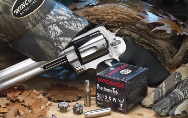 Man-made HD PC desktop wallpaper showing a Smith & Wesson Model 500 revolver, Winchester .500 S&W ammo box, spent rounds, camo cap and fallen leaves.