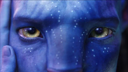 Close-up HD PC desktop wallpaper of a Na'vi character's face from the movie Avatar, highlighting detailed blue skin and striking yellow eyes.
