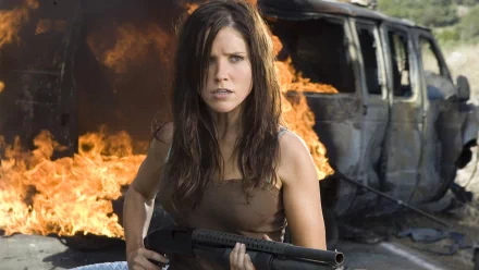 HD PC desktop wallpaper featuring celebrity Sophia Bush holding a shotgun, standing in front of a burning vehicle with intense flames in the background.