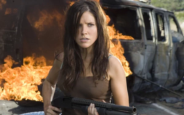 HD PC desktop wallpaper featuring celebrity Sophia Bush holding a shotgun, standing in front of a burning vehicle with intense flames in the background.