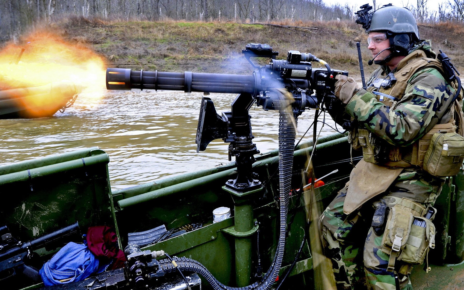 A soldier firing an M134 Minigun mounted on a boat, set in an outdoor environment, captured in high definition for a PC desktop wallpaper background.