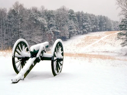 HD PC desktop wallpaper and background: military artillery cannon blanketed in snow on a quiet winter field, frosted trees and rolling hills beyond.