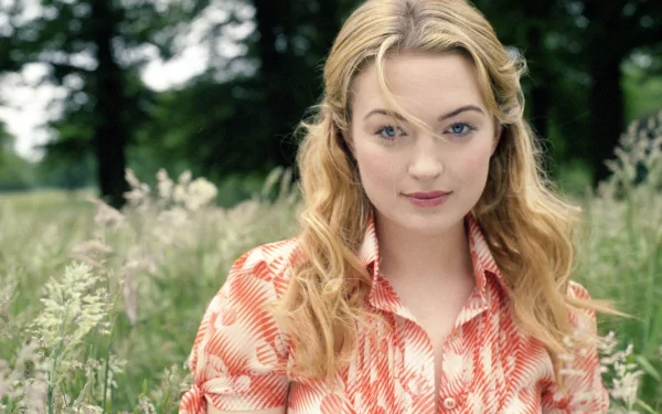 HD desktop wallpaper featuring celebrity Sophia Myles with natural makeup and wavy hair, posing outdoors in a field of tall grass.