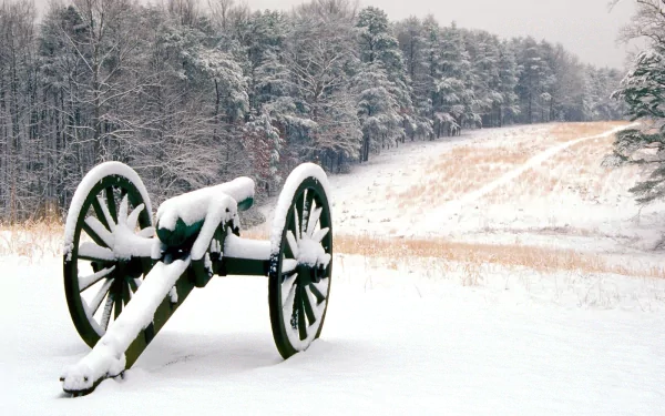 HD PC desktop wallpaper and background: military artillery cannon blanketed in snow on a quiet winter field, frosted trees and rolling hills beyond.