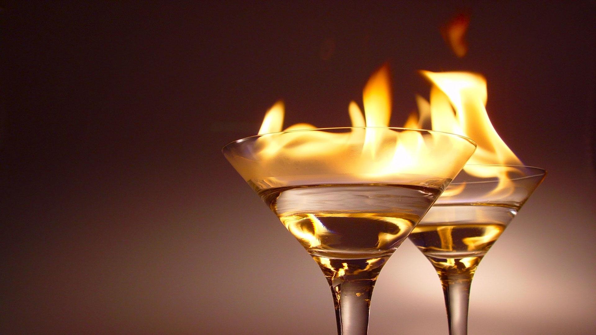 HD desktop wallpaper showing two elegant glass cocktails with flames flickering above the drinks, creating a striking and dynamic food and drink visual.