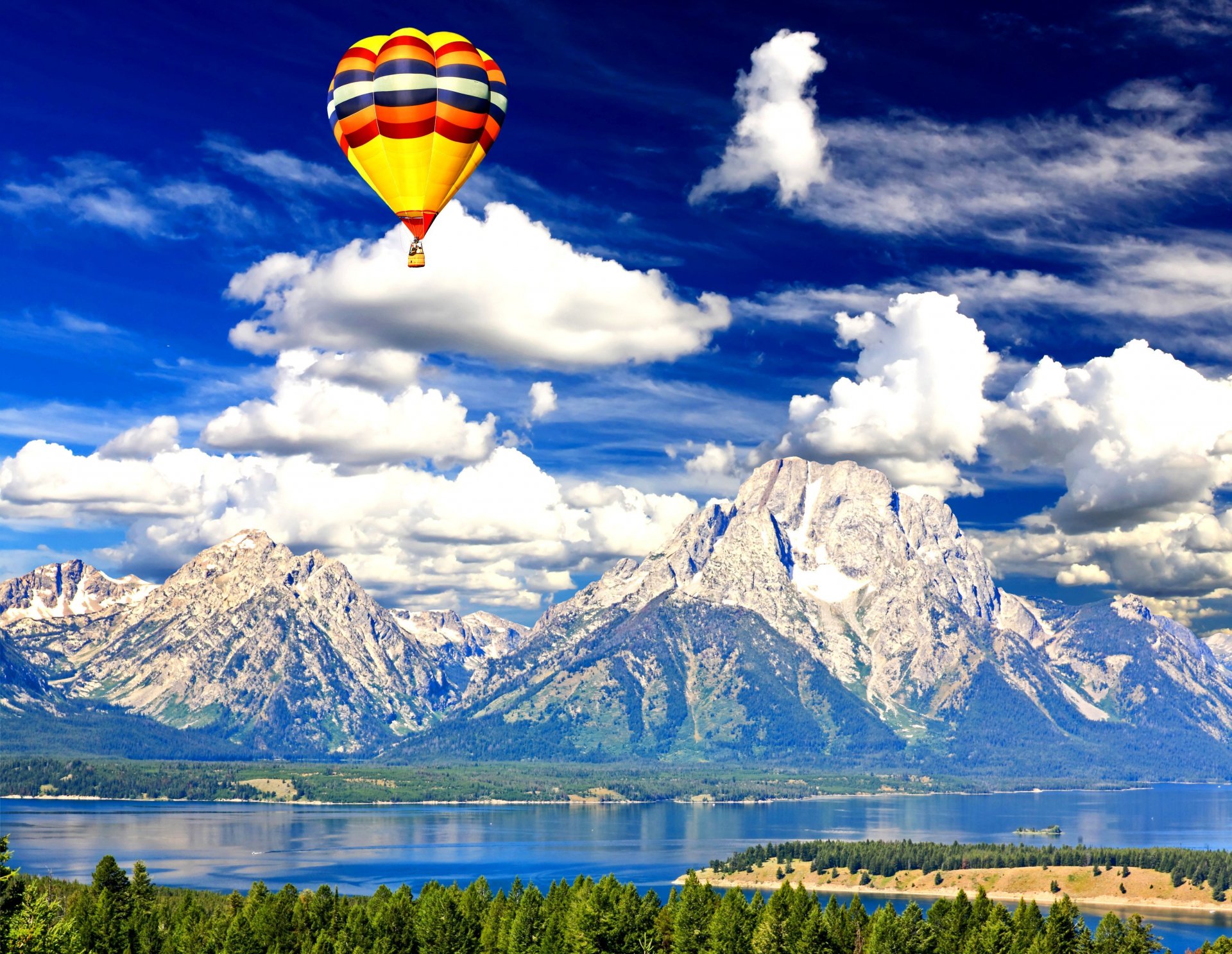 4K Ultra HD PC desktop wallpaper: a colorful hot air balloon vehicle floats over a tranquil lake with towering snow-capped mountains beneath dramatic cloud-filled skies.