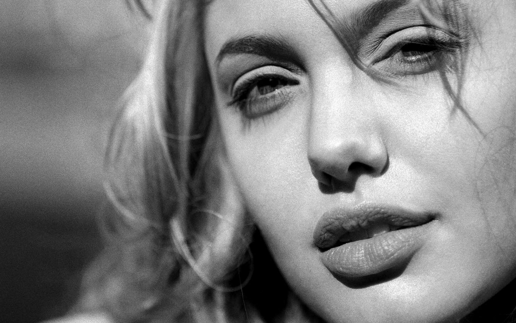 Close-up portrait of Angelina Jolie in black and white, showcasing her striking features. This image serves as an HD desktop wallpaper and background.