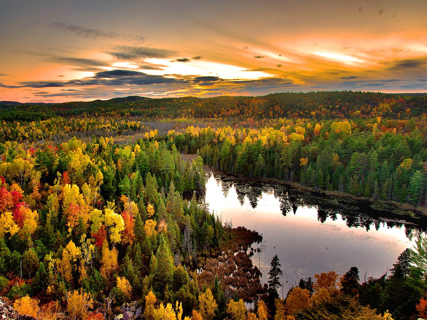 HD PC desktop wallpaper showcasing a scenic nature view of a river winding through a vibrant forest under a dramatic sunset sky.