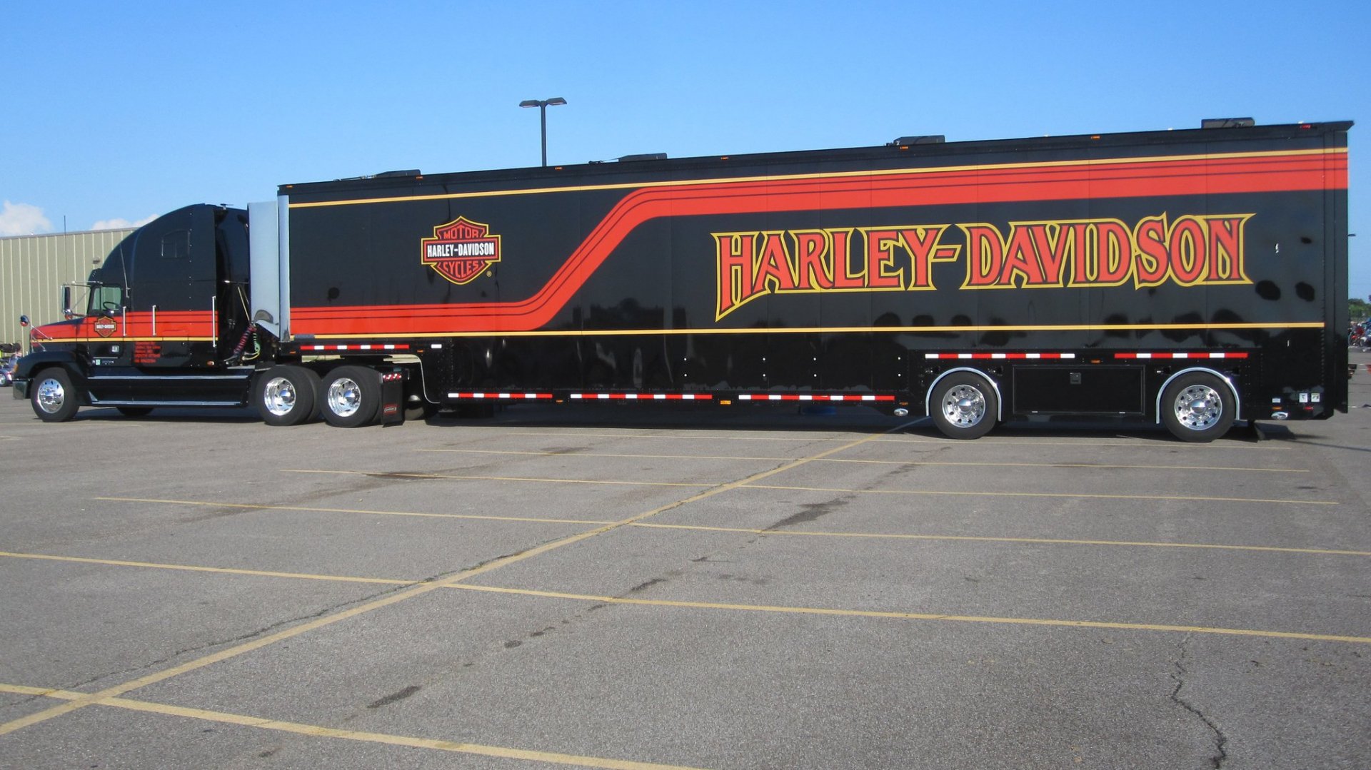 A sleek black truck with bold red and yellow Harley-Davidson branding, parked in a lot, serving as a high-definition desktop wallpaper and background.