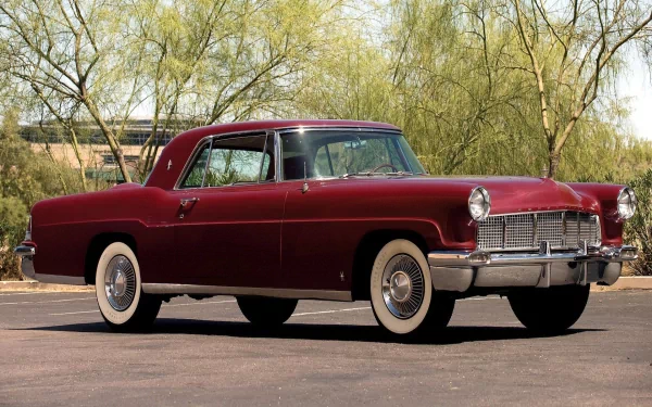 A classic red Lincoln Continental parked against a backdrop of greenery, showcased as a high-definition desktop wallpaper and background.