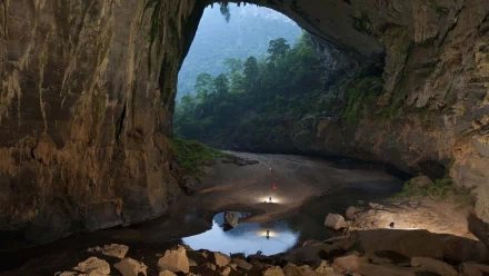 HD desktop wallpaper showcasing the vast Son Doong Cave with natural light illuminating its rocky interior and lush greenery beyond.
