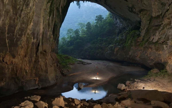 HD desktop wallpaper showcasing the vast Son Doong Cave with natural light illuminating its rocky interior and lush greenery beyond.
