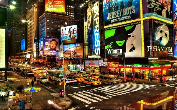 Vibrant nighttime view of Manhattan's Times Square in New York, showcasing illuminated billboards, bustling streets, and yellow taxis in this HD cityscape wallpaper.