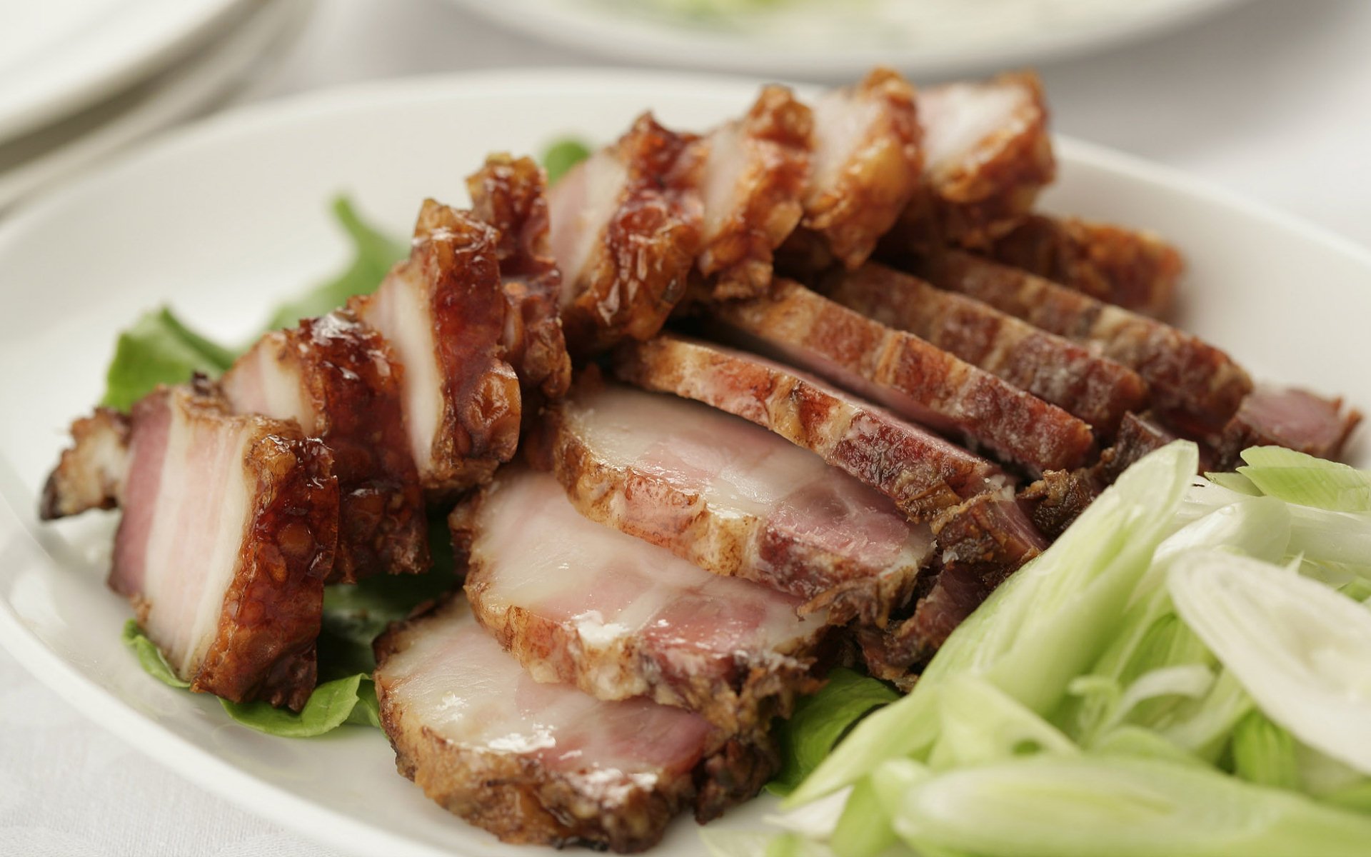 HD desktop wallpaper featuring a close-up of sliced Chinese roasted pork arranged on lettuce with a side of fresh vegetable garnish.