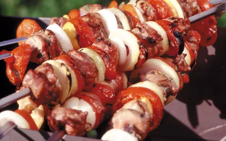 HD desktop wallpaper featuring close-up of vibrant barbecue skewers loaded with grilled meat, onions, and bell peppers, showcasing delicious food and barbecue themes.