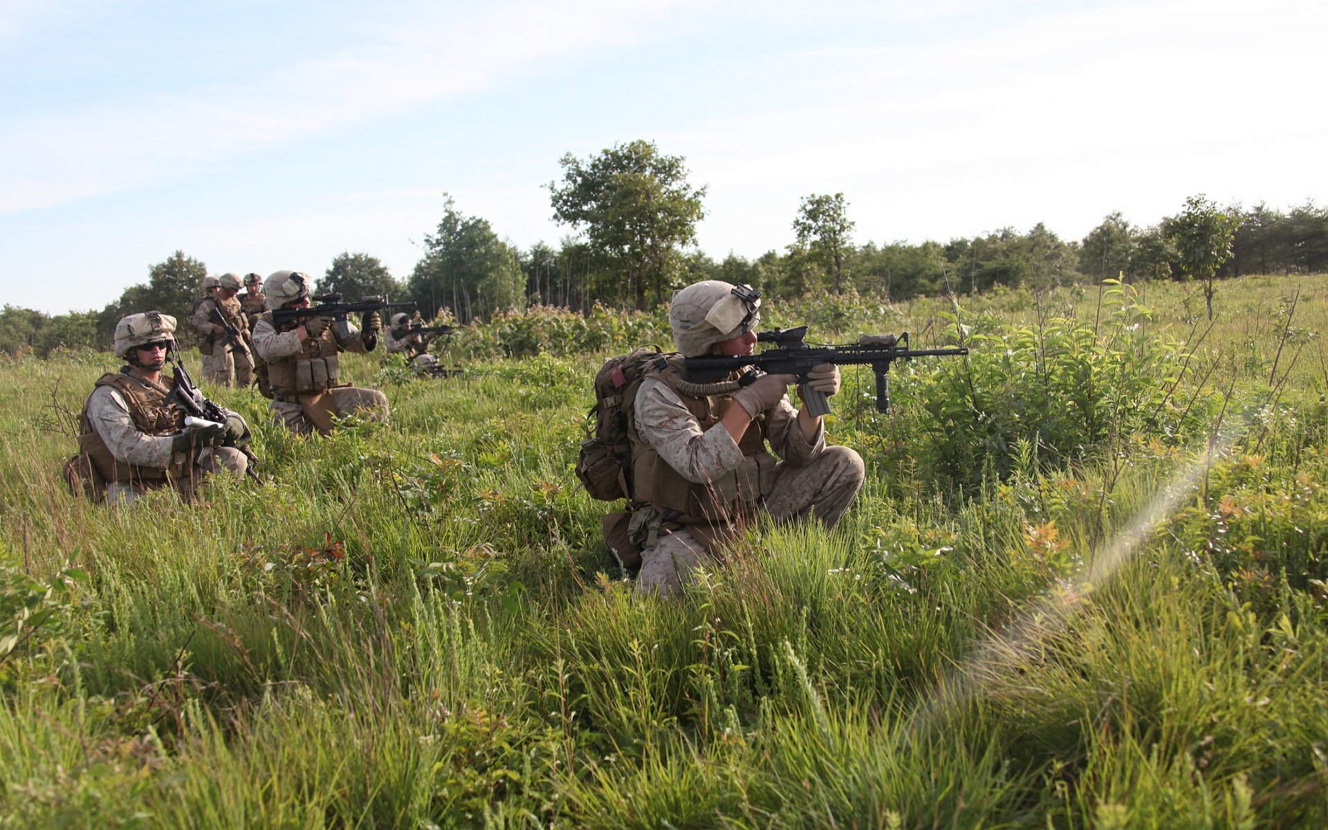HD desktop wallpaper showing U.S. Army Infantry soldiers armed with guns, positioned in a grassy field during a military operation.