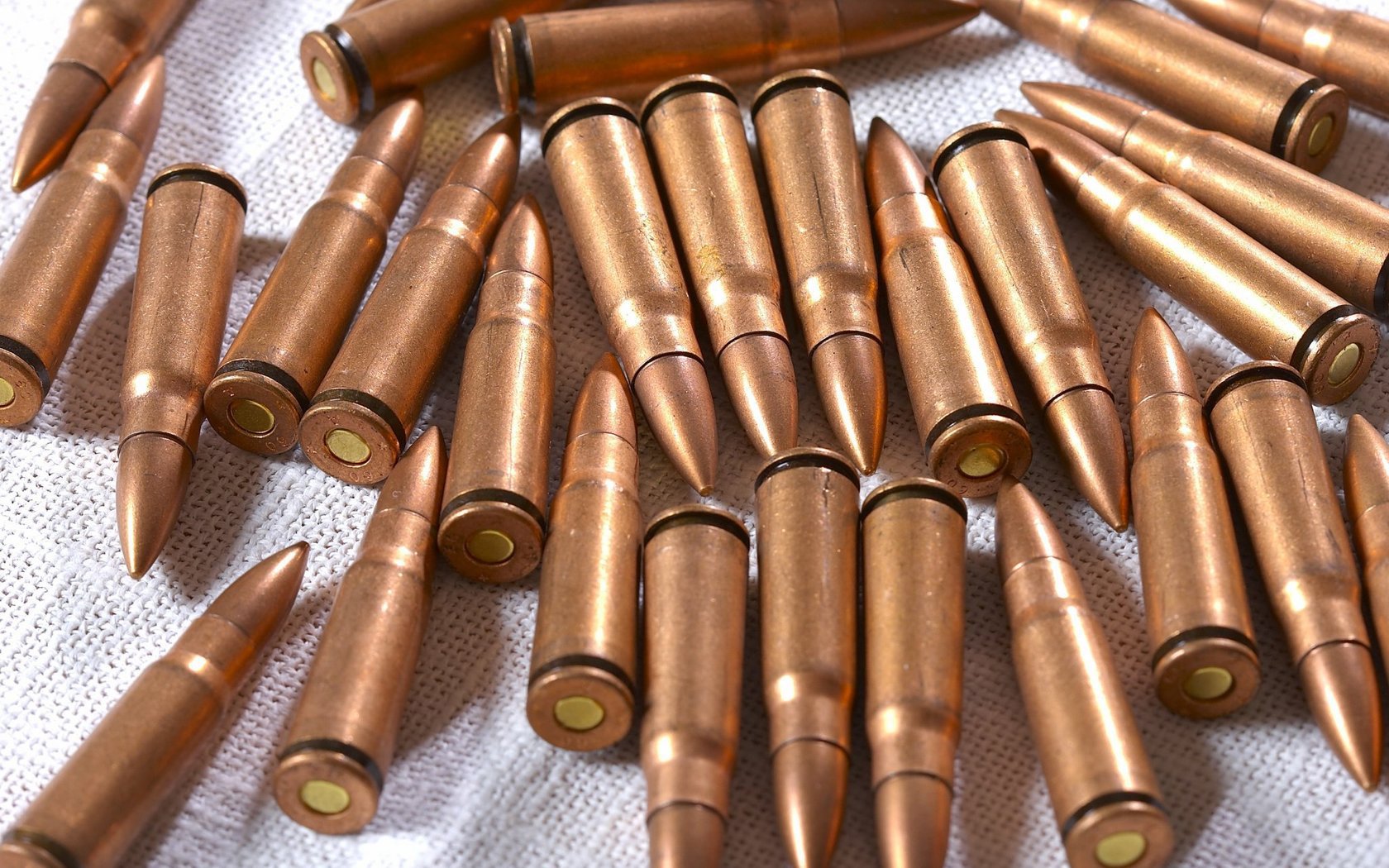 Close-up of man-made bullets scattered on a surface, captured in high definition for use as a PC desktop wallpaper background.