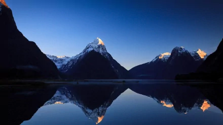 HD PC desktop wallpaper/background — Milford Sound nature scene: snow-capped mountains reflected in a glassy lake at dawn.