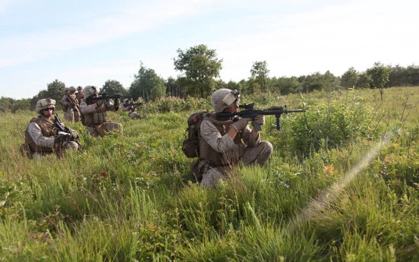HD desktop wallpaper showing U.S. Army Infantry soldiers armed with guns, positioned in a grassy field during a military operation.