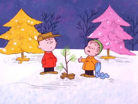 Charlie Brown and Linus van Pelt from A Charlie Brown Christmas stand in the snow, discussing a small Christmas tree, with colorful trees in the background. HD desktop wallpaper.