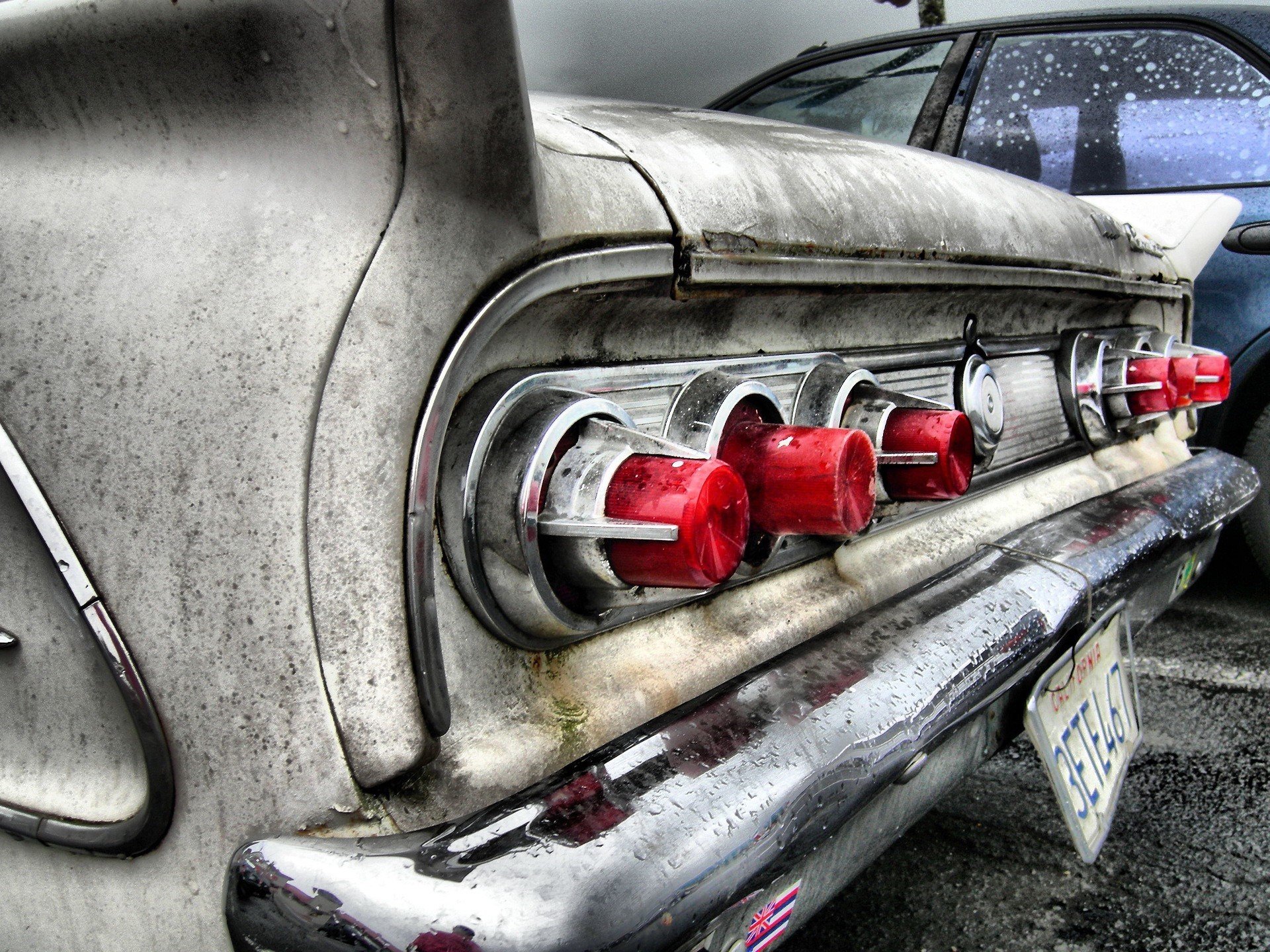 An artistic HD desktop wallpaper featuring the back of an old vehicle, showcasing its vintage design and distinctive red tail lights with a weathered finish.