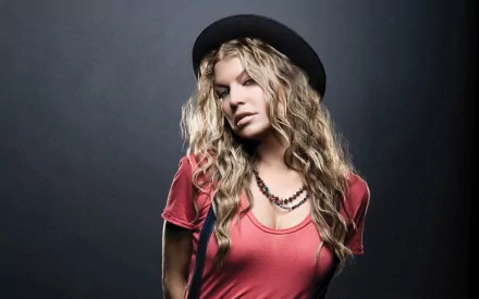 A striking HD wallpaper featuring Fergie, showcasing her unique style with wavy hair, a stylish hat, and a vibrant red top against a dramatic dark background.