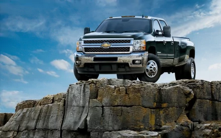 HD PC desktop wallpaper: Chevrolet vehicle — a pickup truck perched on a rocky cliff under a dramatic blue sky, rugged automotive background.
