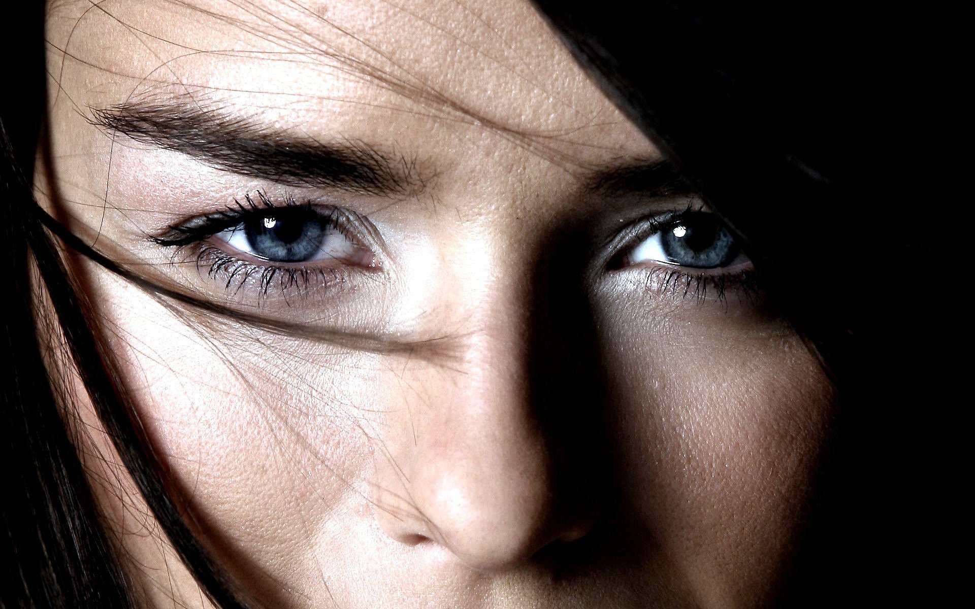 Close-up HD desktop wallpaper of a woman with black hair and striking blue eyes, featuring Jessica Nigri.