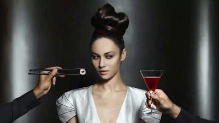 HD PC desktop wallpaper featuring celebrity Olga Kurylenko in a sleek white outfit, holding a red cocktail, with a pair of chopsticks offering sushi.
