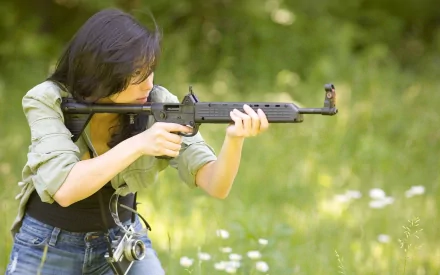 A woman takes aim with a firearm in a lush outdoor setting, blending strength and determination in this HD desktop wallpaper, showcasing the theme of Girls & Guns.