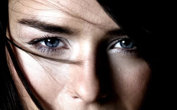 Close-up HD desktop wallpaper of a woman with black hair and striking blue eyes, featuring Jessica Nigri.