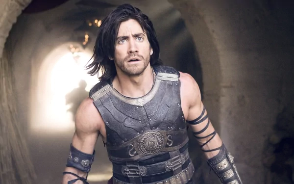 Jake Gyllenhaal as the Prince in *Prince of Persia: The Sands of Time*, captured in a dramatic moment in a dimly lit corridor, serving as an HD desktop wallpaper.