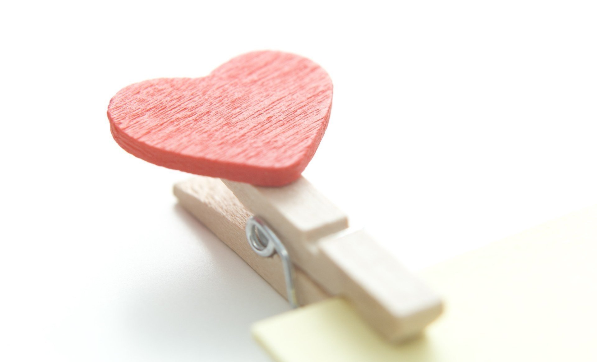 A close-up of a wooden clothespin holding a red heart, symbolizing love. This artistic image serves as a vibrant HD desktop wallpaper and background.