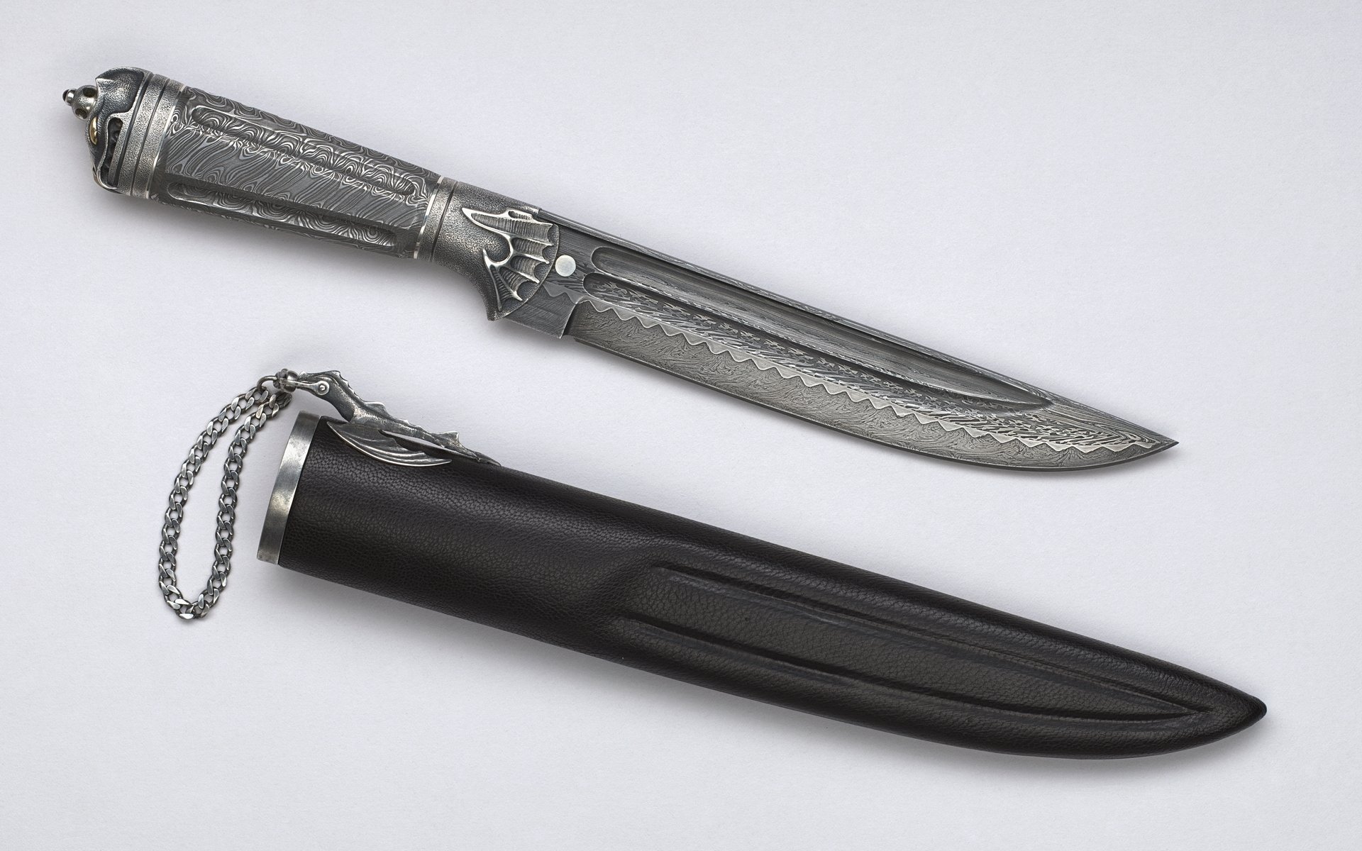 An intricate knife with a detailed handle sits next to a sleek black sheath, featured as a high-definition PC desktop wallpaper and background.