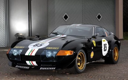 HD PC desktop wallpaper/background showing a black classic sports car (No. 85) with white and green racing stripes and gold rims, parked in front of a closed garage door.