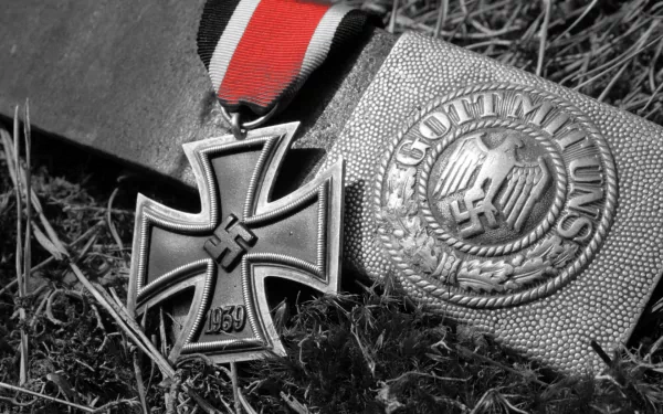 HD PC desktop wallpaper: black-and-white close-up of military medals — Iron Cross and Gott mit uns belt buckle with swastikas resting on grass.