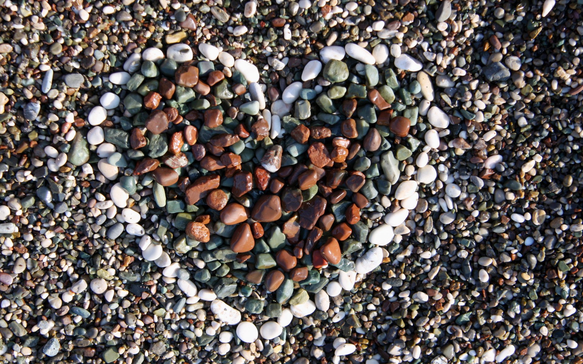 Artistic HD desktop wallpaper featuring a heart shape made from colorful pebbles arranged on a gravel background, symbolizing love and natural beauty.