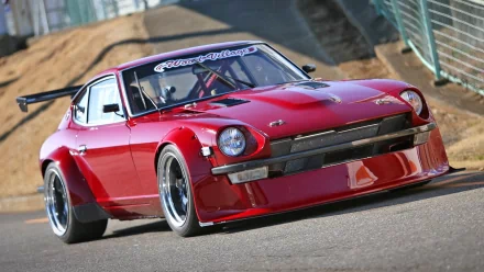 HD PC desktop wallpaper featuring a sleek red sports car parked on a racetrack, showcasing its aerodynamic design and polished finish.