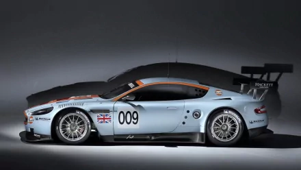 HD PC desktop wallpaper and background showing a silver racing sports car vehicle (side profile) marked 009 with British flag, aerodynamic body and rear wing on a neutral studio backdrop.