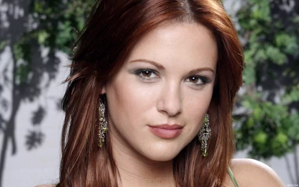 Close-up portrait of Danneel Harris with red hair and elegant earrings, set against a blurred natural background, featured as a HD PC desktop wallpaper.