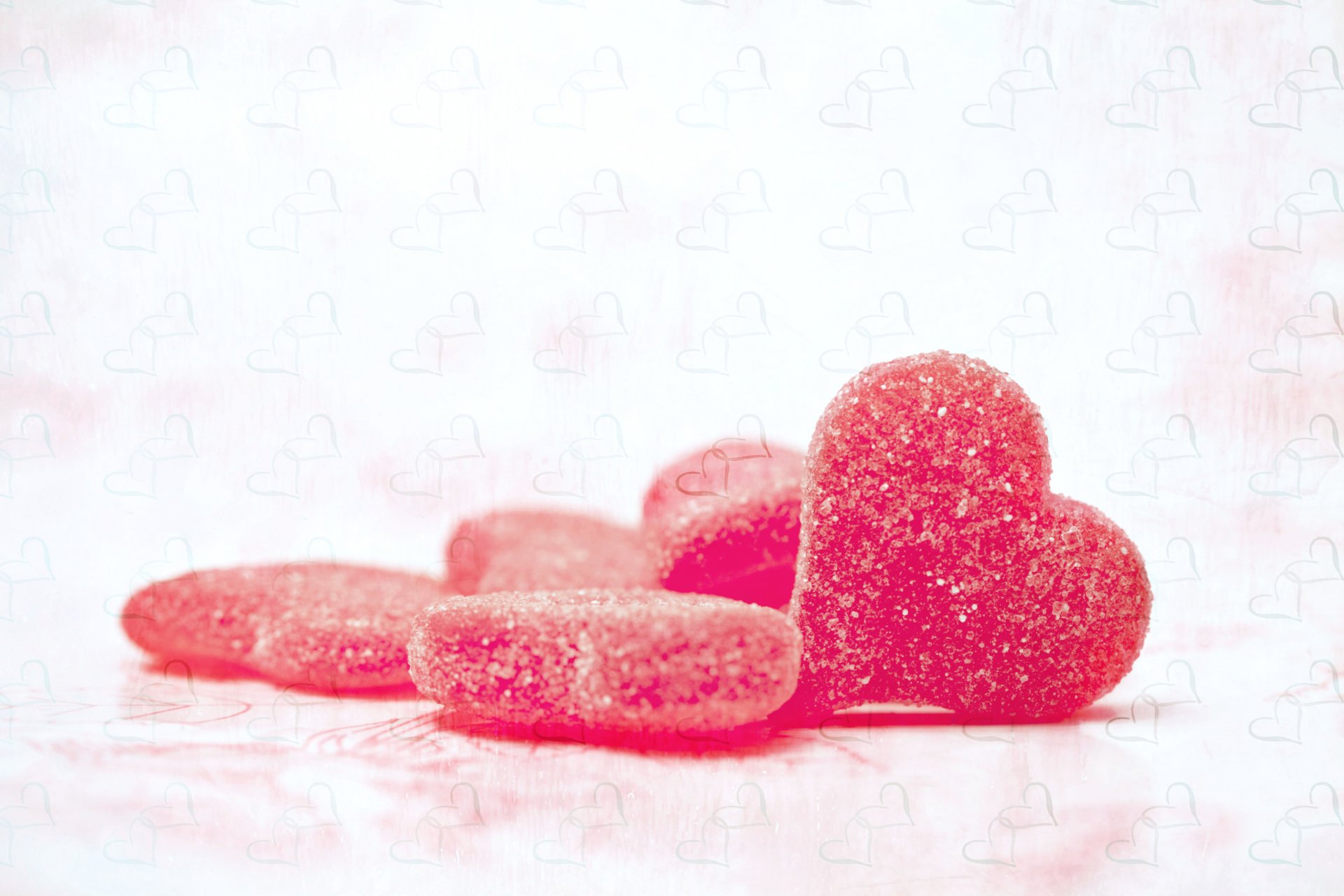 HD artistic desktop wallpaper featuring sugar-coated heart-shaped candies against a soft pink and white background, evoking the theme of love.