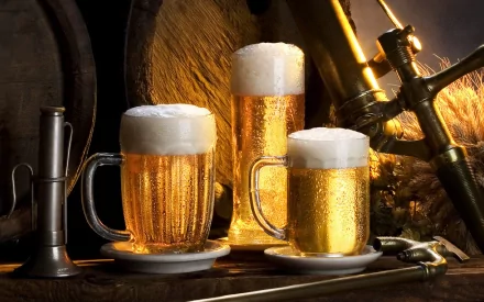 HD PC desktop wallpaper featuring three frosty mugs of golden beer with foam, set against a warm, rustic backdrop of wooden barrels and brewing equipment.